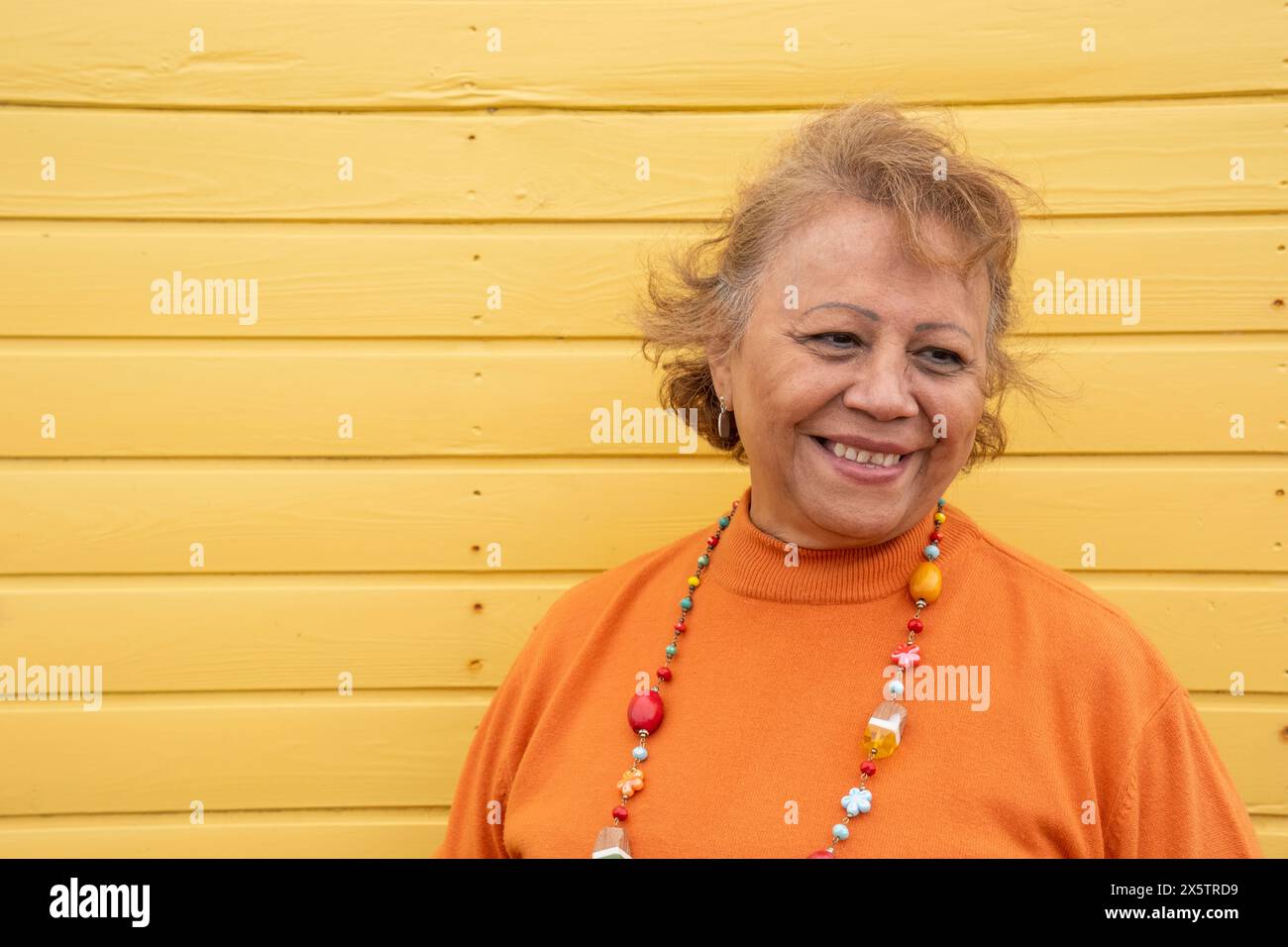 Porträt einer lächelnden Seniorin an der gelben Wand Stockfoto