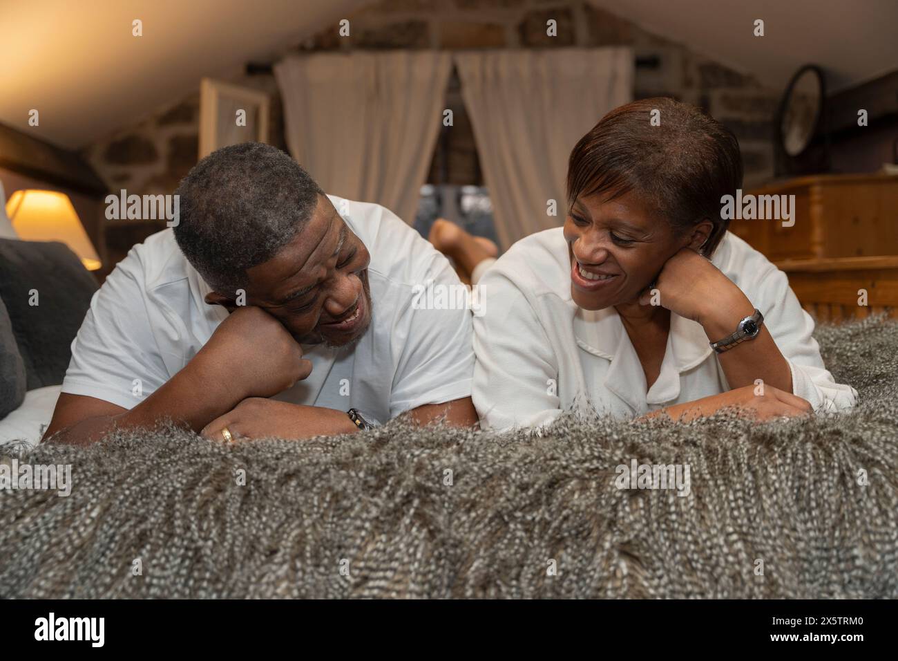 Lächelndes Seniorenpaar, das vorne im Schlafzimmer liegt Stockfoto