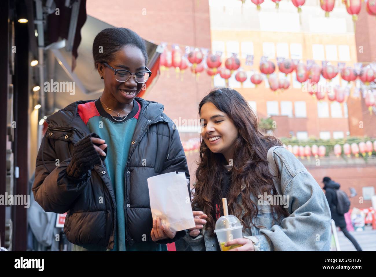Porträt von zwei fröhlichen Frauen mit Essen zum Mitnehmen in Chinatown Stockfoto