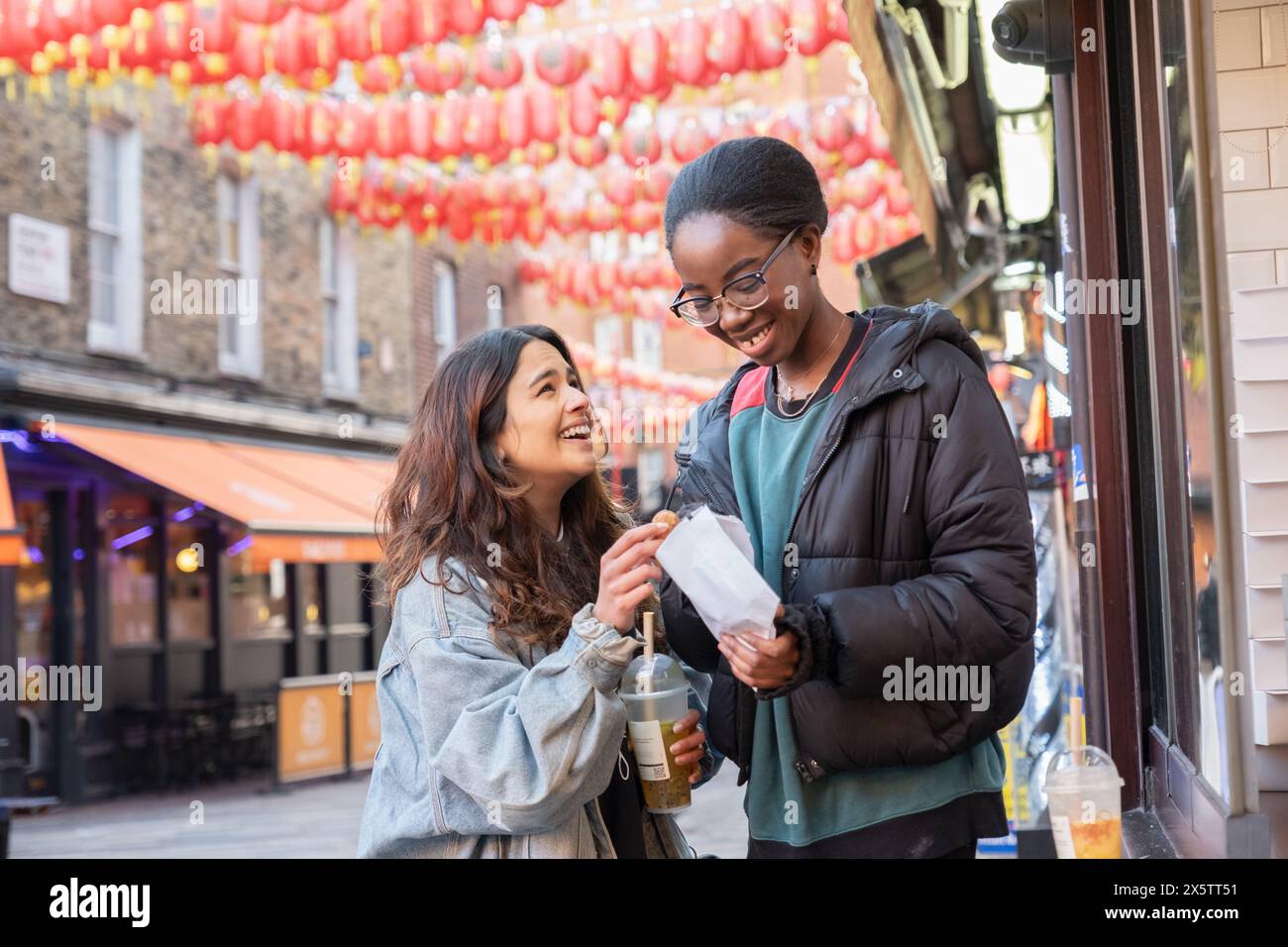 Porträt von zwei fröhlichen Frauen mit Essen zum Mitnehmen in Chinatown Stockfoto