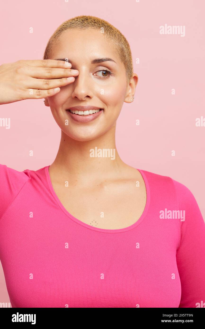 Lächelnde blonde Frau, die ein Auge abschirmt Stockfoto