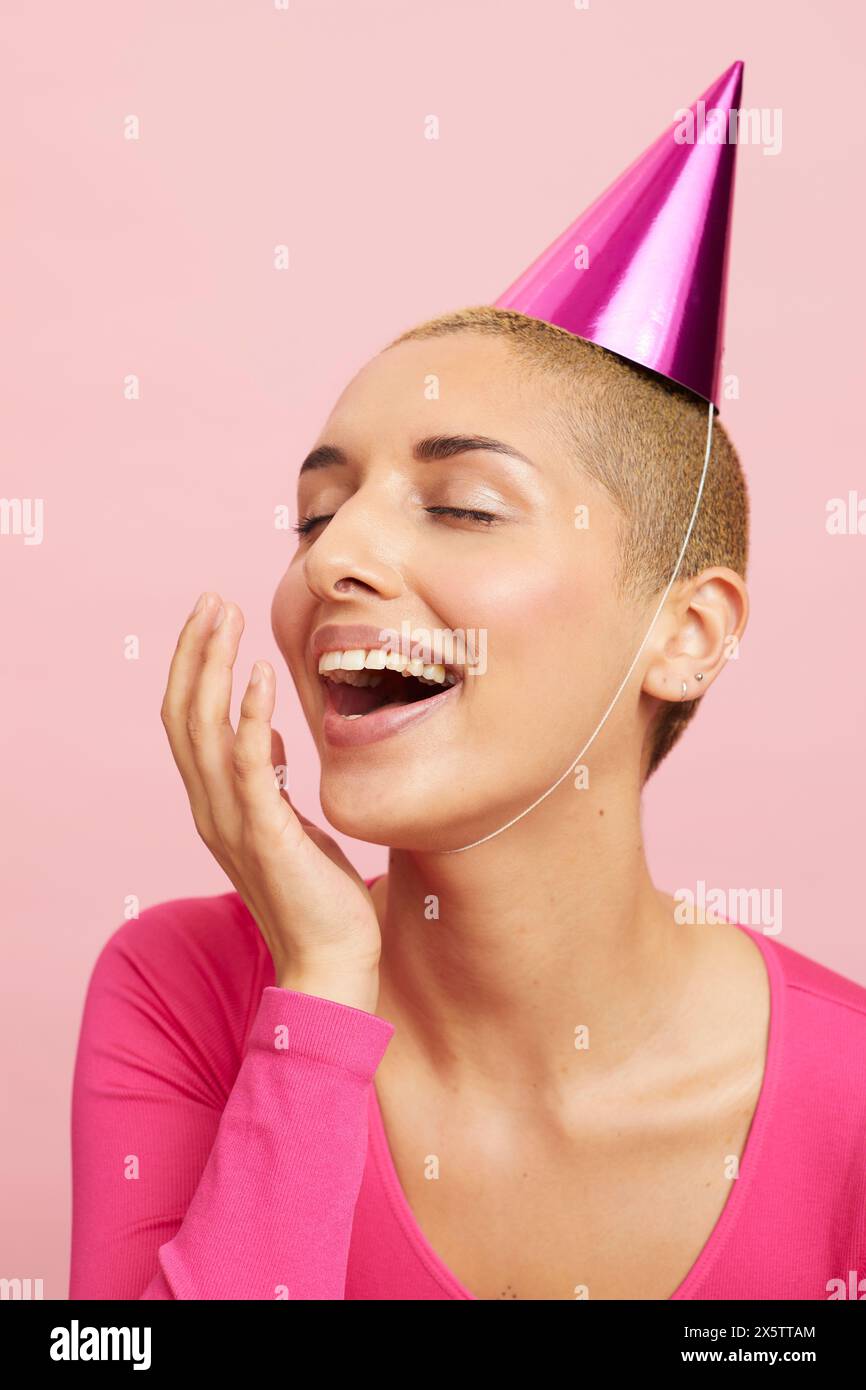 Lachende Frau mit rosa Partyhut Stockfoto