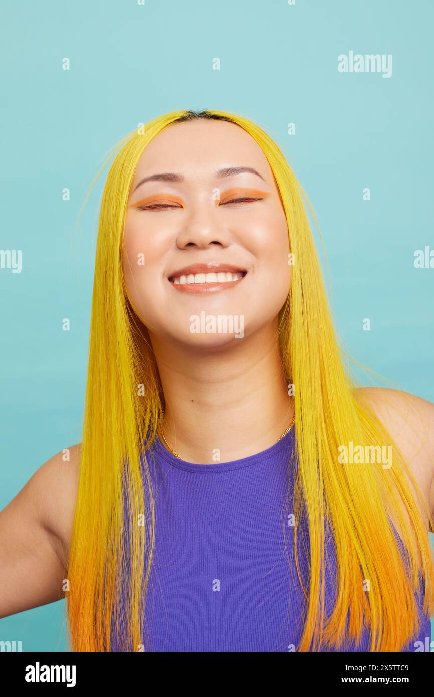 Porträt einer lächelnden Frau mit langen gelben Haaren und geschlossenen Augen Stockfoto