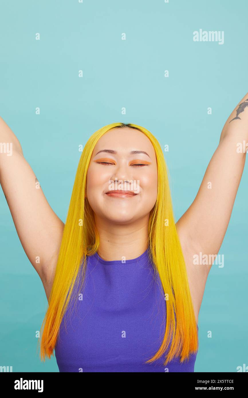 Eine junge Frau mit langen gelben Haaren, die Arme hochhebt Stockfoto