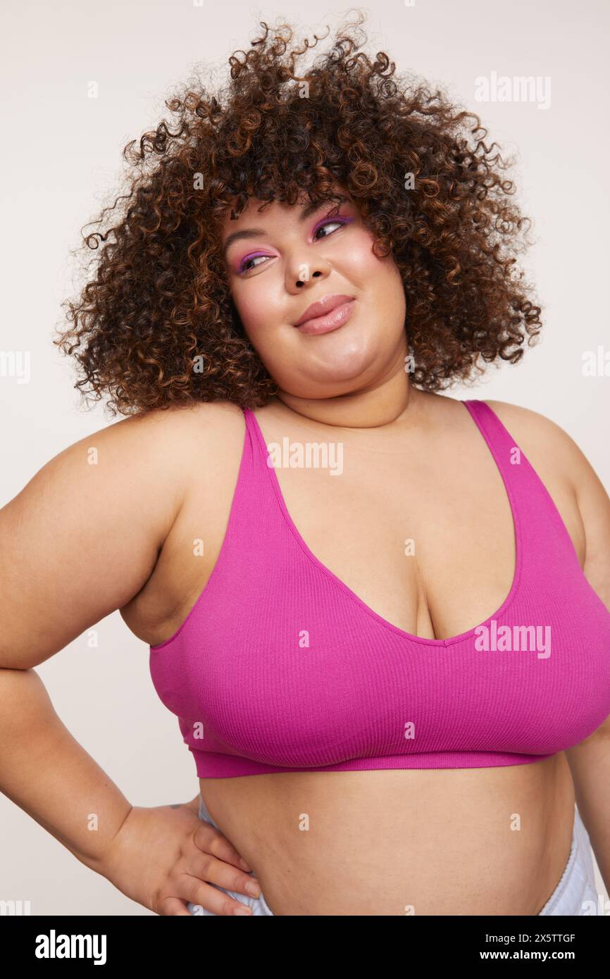Brünette, die einen rosa BH trägt, die Hand an der Hüfte hält Stockfoto