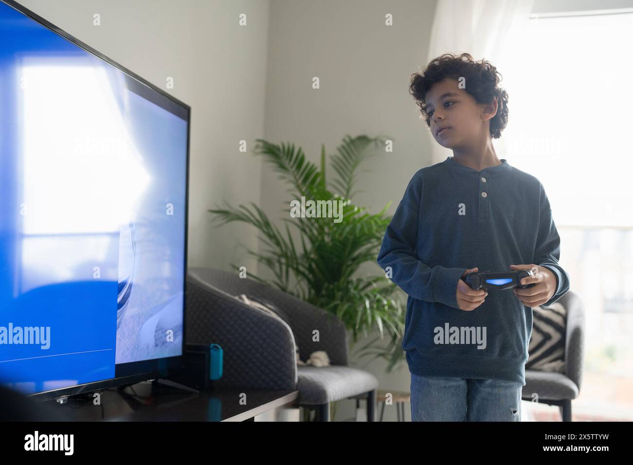 Junge (6-7) spielt Videospiel im Fernsehen Stockfoto