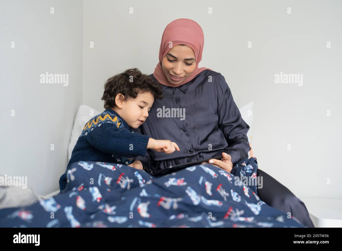 Mutter und Sohn (2-3) mit digitalem Tablet im Bett Stockfoto