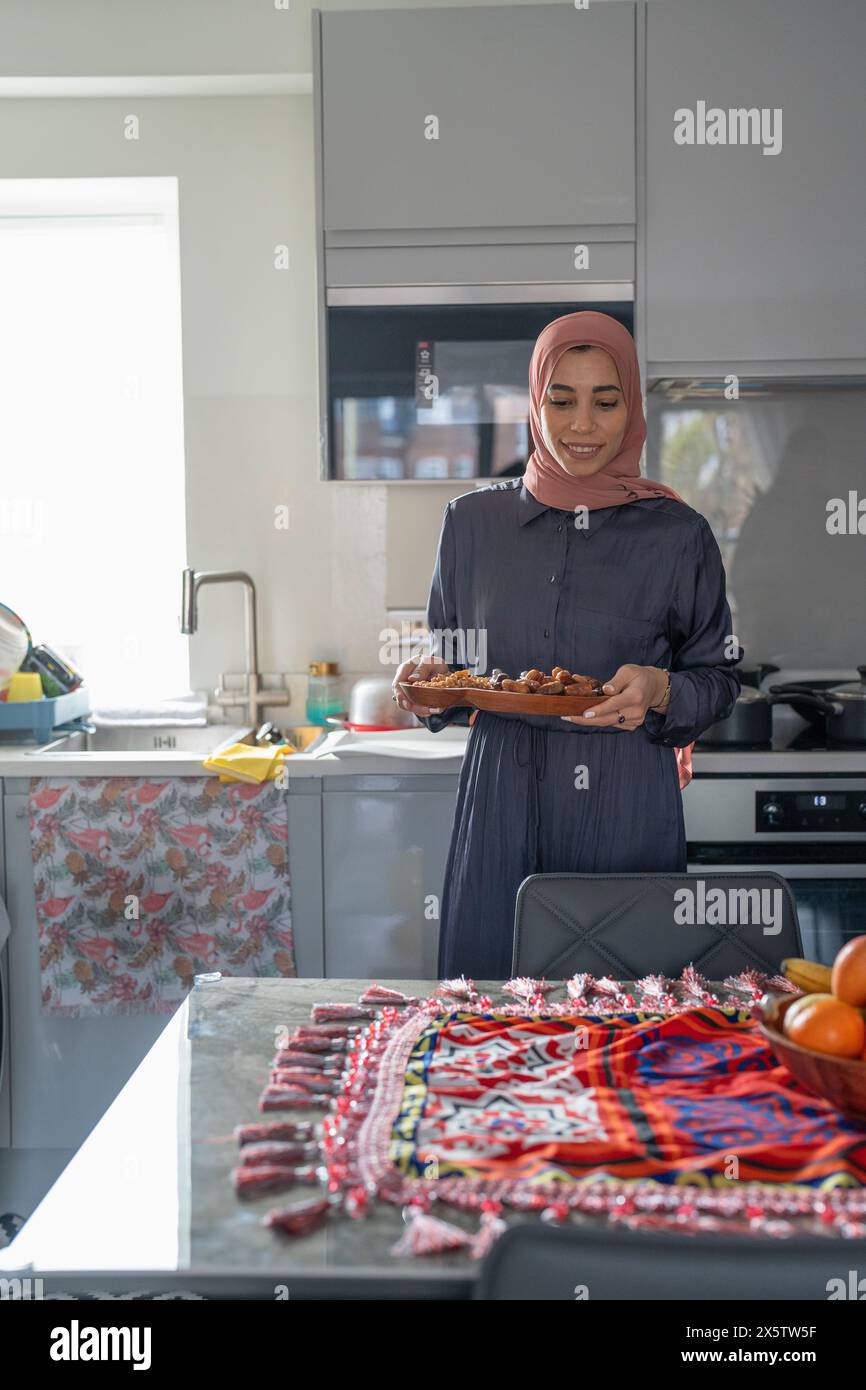 Lächelnde Frau im Hijab, die Essen auf den Tisch legt Stockfoto