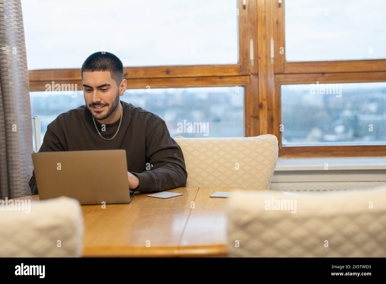 Junger Mann am Laptop zu Hause arbeiten Stockfoto