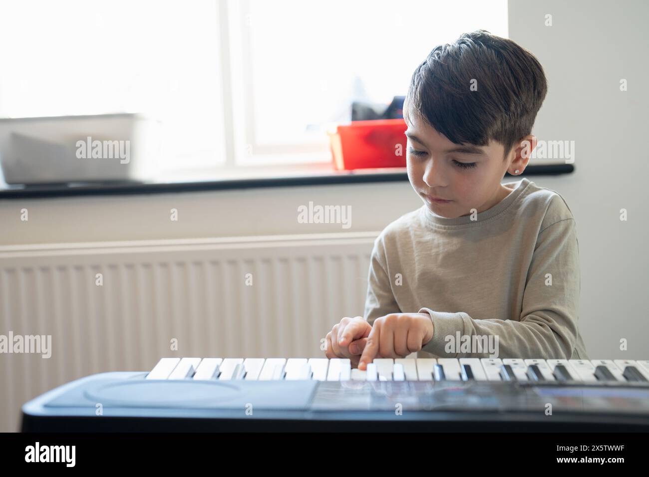 Junge (6–7) spielt zu Hause Musik-Keyboard Stockfoto