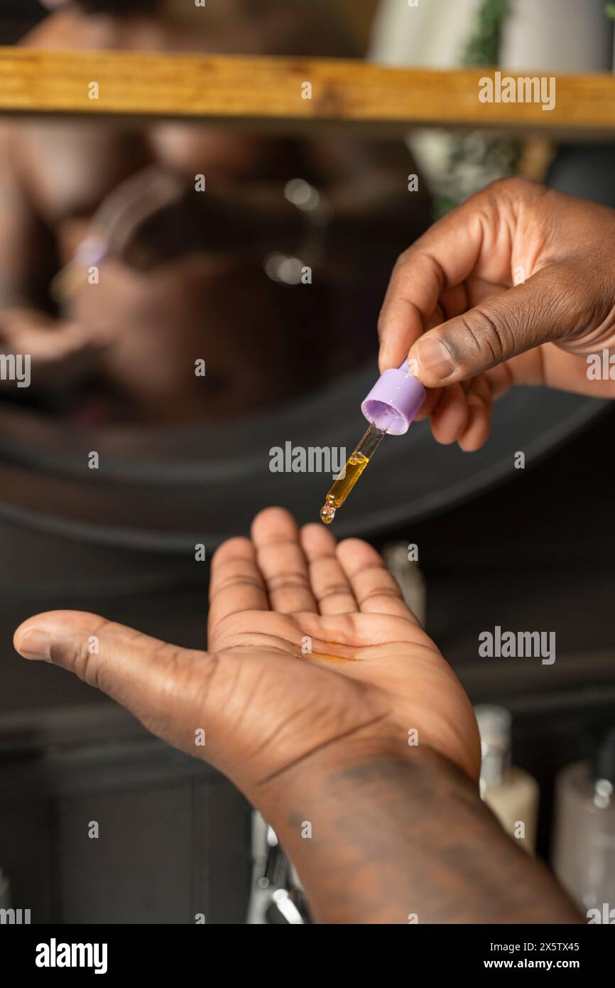 Mann, der Schönheitsprodukt mit Pipette auf die Hand aufträgt Stockfoto