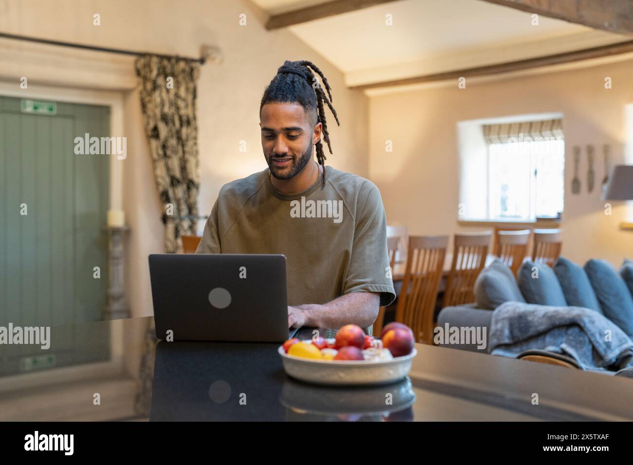 Mann mit Dreads, der zu Hause am Laptop arbeitet Stockfoto