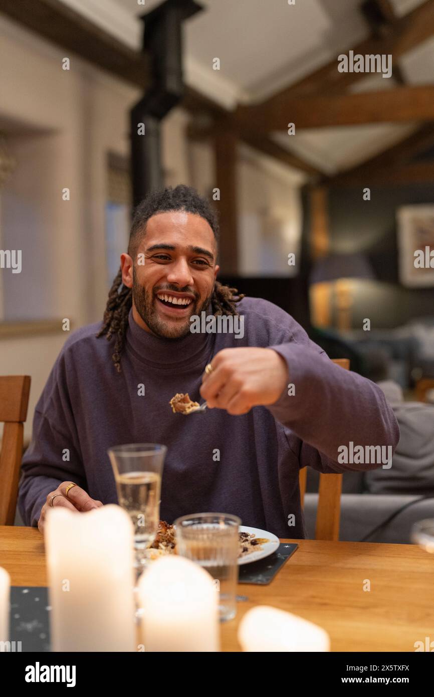 Ein lächelnder Mann isst am Tisch zu Abend Stockfoto