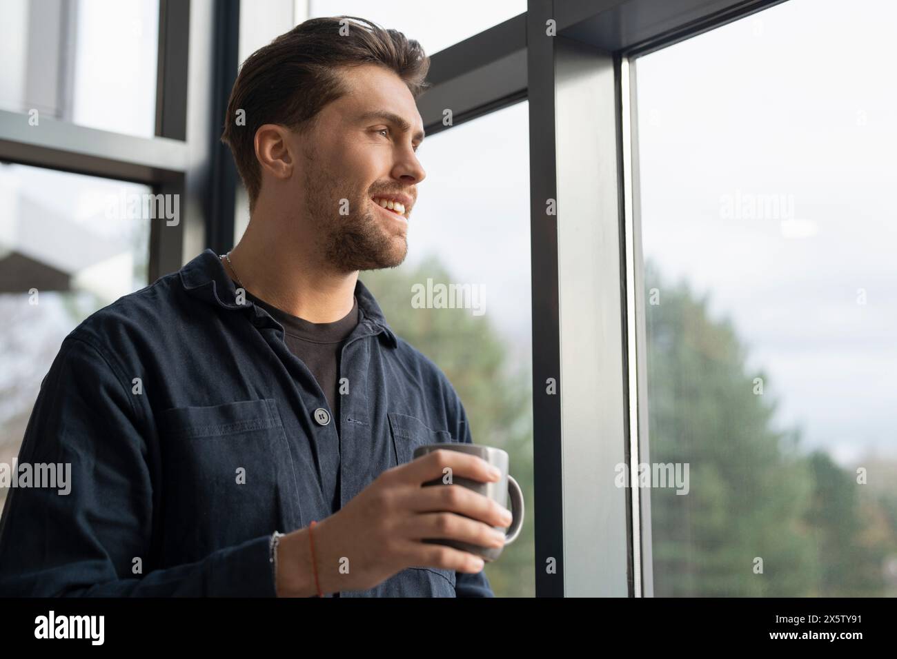 Geschäftsmann trinkt Kaffee und schaut durch das Bürofenster Stockfoto