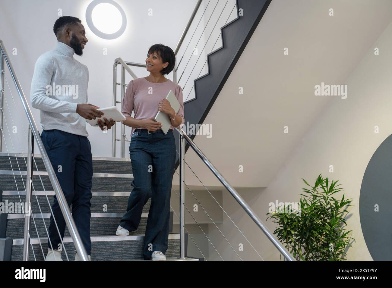 Geschäftsleute gehen die Treppe runter und reden im Büro Stockfoto