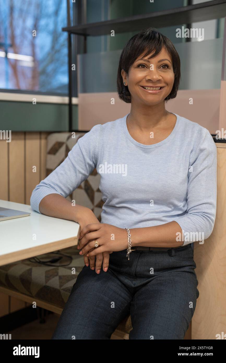 Lächelnde, reife Geschäftsfrau, die im Amt sitzt Stockfoto