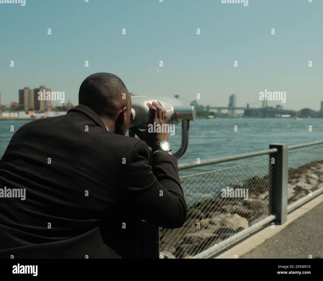USA, New York City, Mann im Anzug, der die Stadt mit einem Münzfernglas ansieht Stockfoto