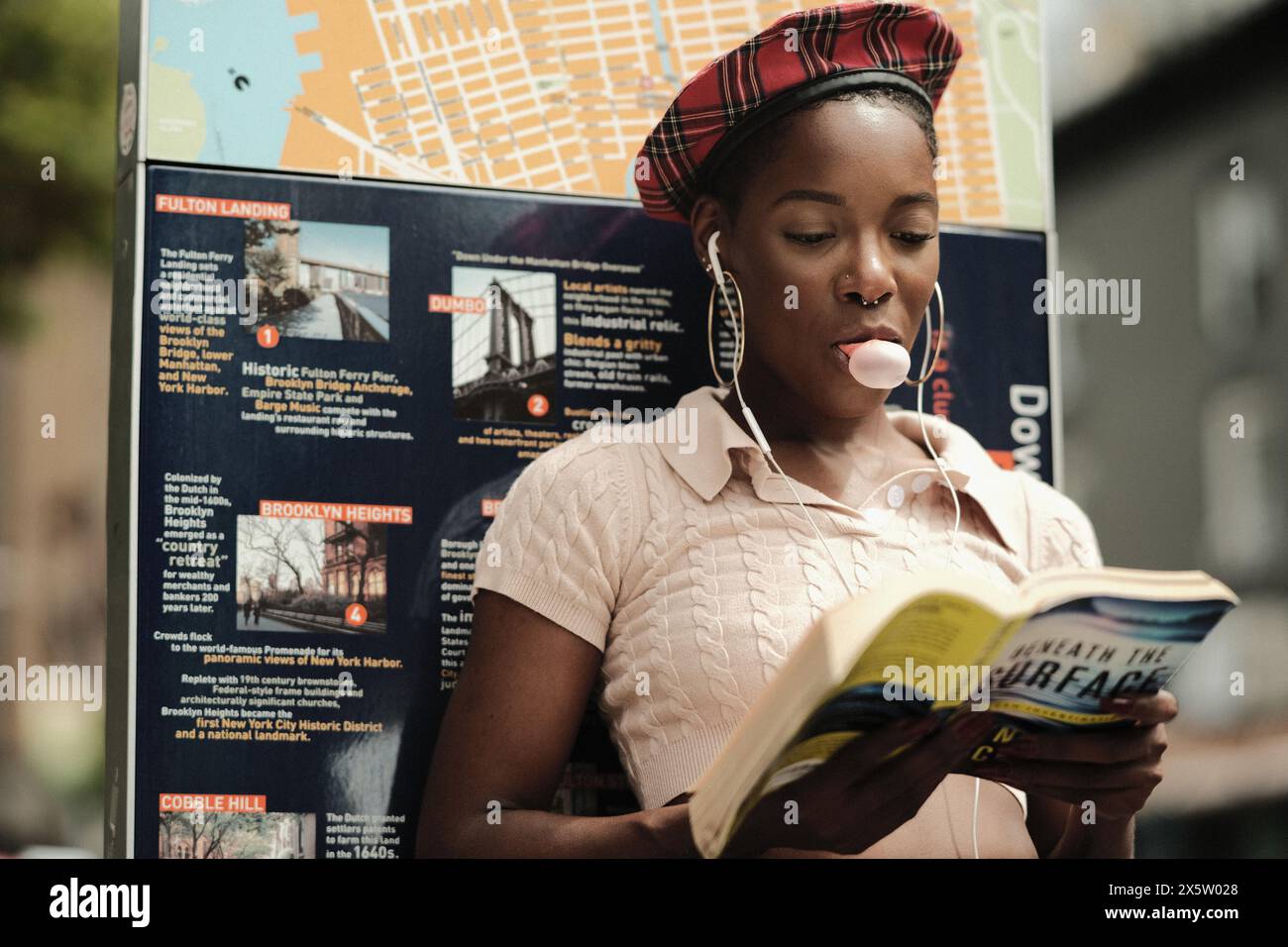 USA, New York, schicke Frau, die Buch liest und Kaugummi in der Stadt bläst Stockfoto