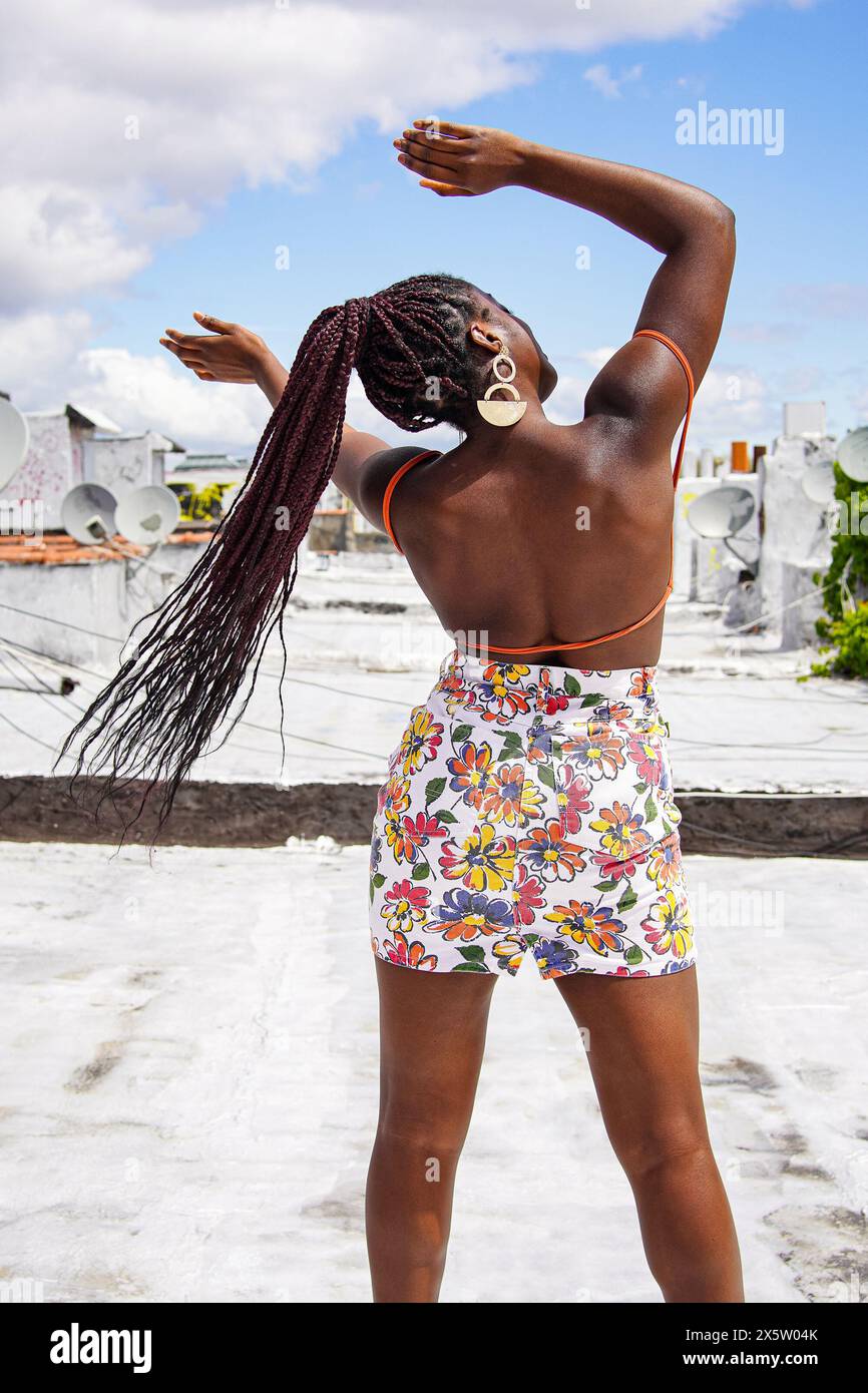 Rückansicht einer Frau im Minirock, die auf dem Dach tanzt Stockfoto