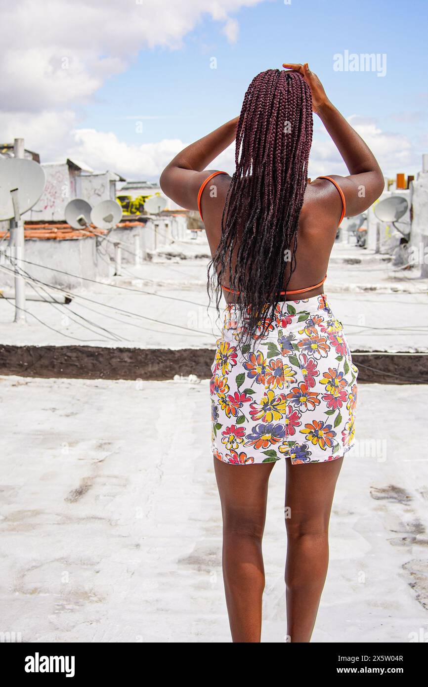 Rückansicht einer Frau im Minirock, die auf dem Dach steht Stockfoto