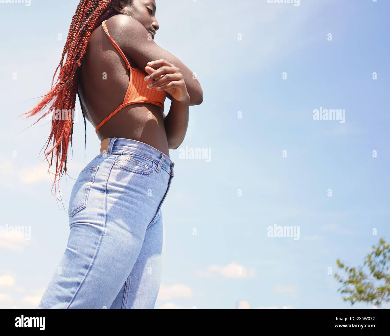 Stilvolle Frau mit überkreuzten Armen im Freien Stockfoto