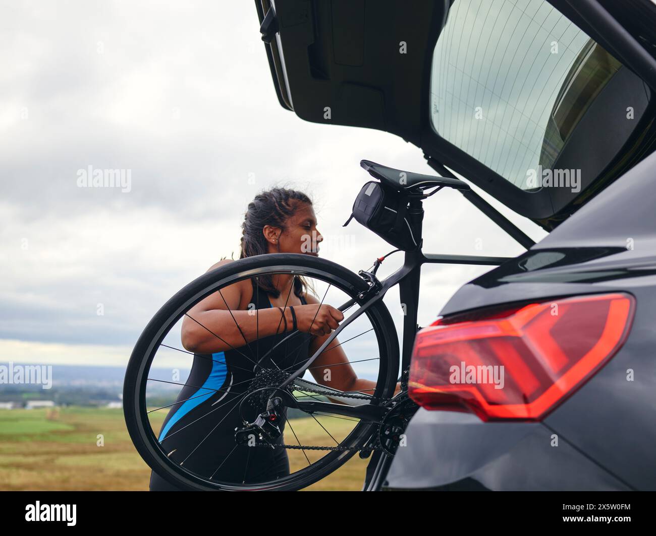 Frau, die Fahrrad aus dem Kofferraum nimmt Stockfoto