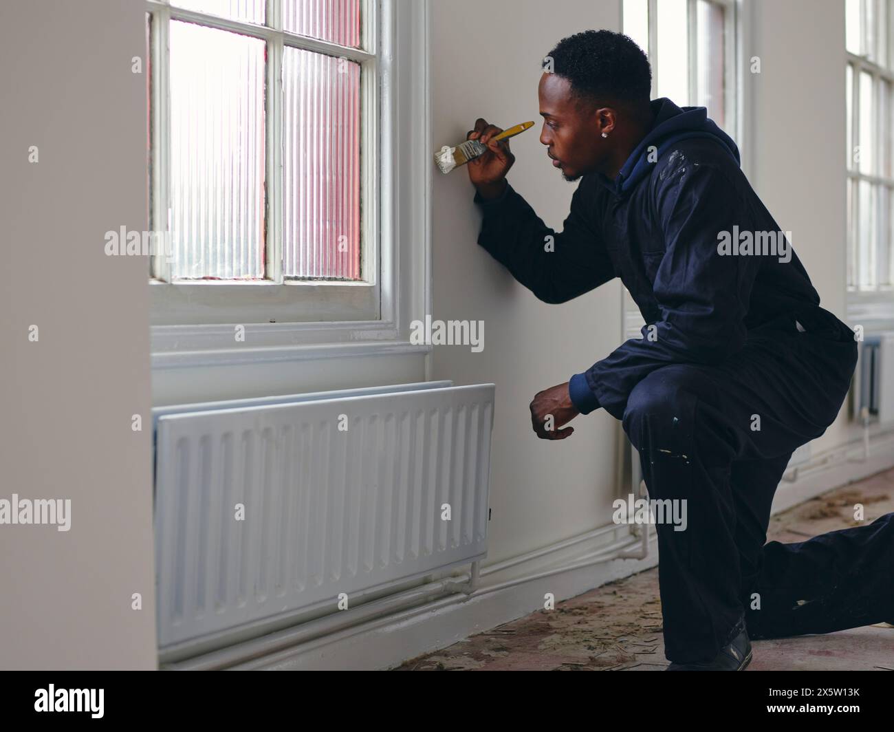 Mann malt Hauswände weiß Stockfoto