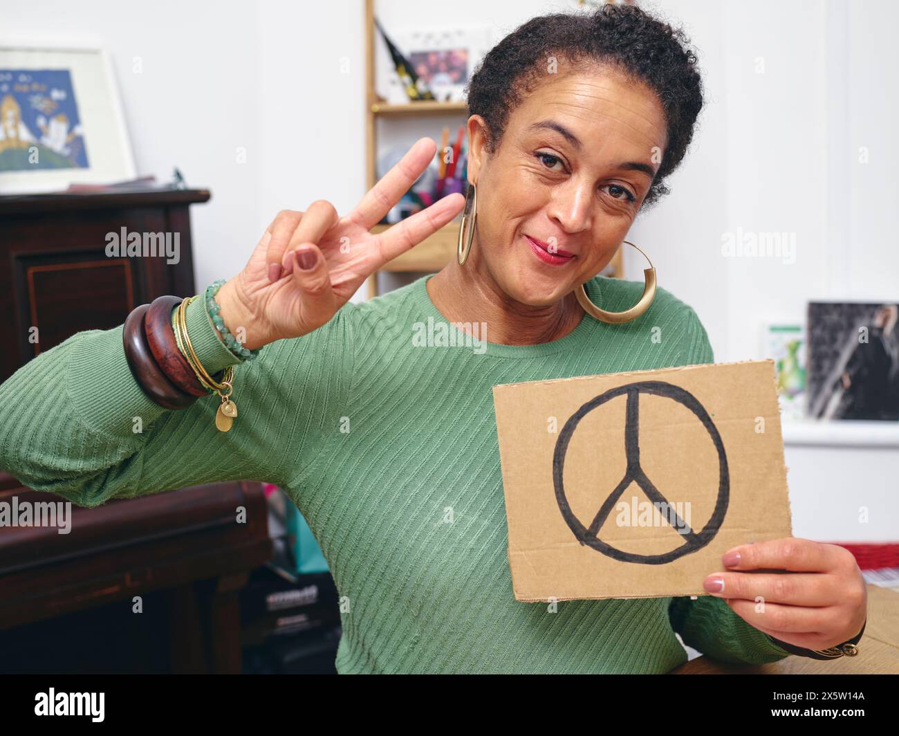 Frau im Zimmer, die ein Protestzeichen mit einem Friedenssymbol hält Stockfoto