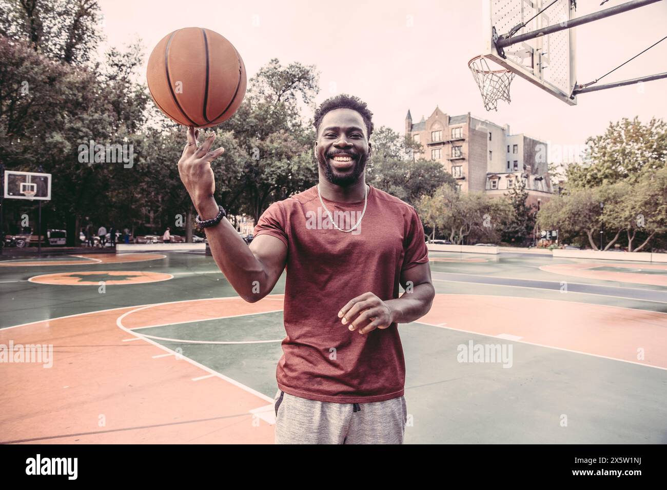 USA, Pennsylvania, Philadelphia, ein lächelnder Mann, der Basketballball auf der Fingerspitze dreht Stockfoto