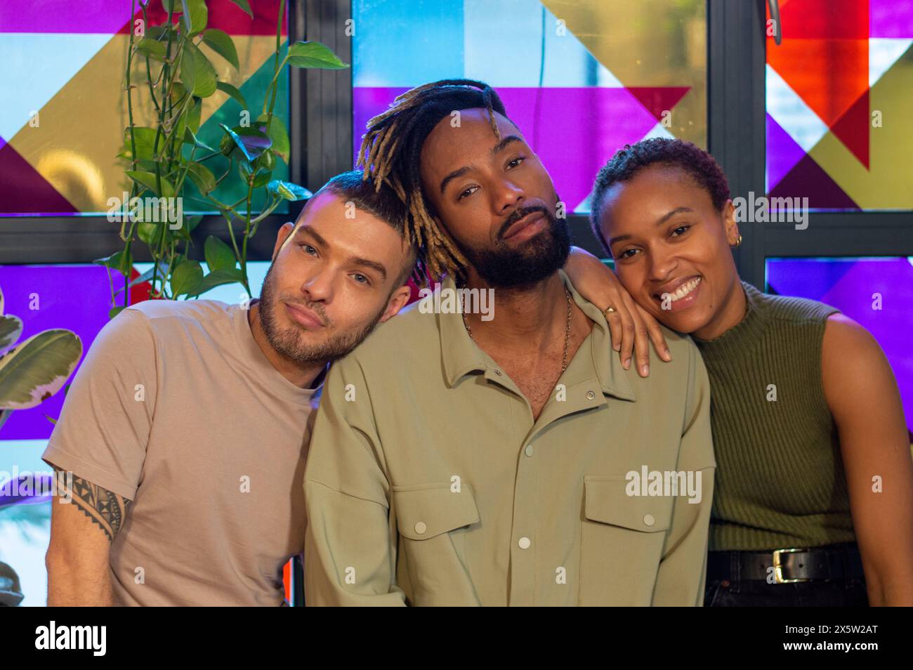 Porträt von Freunden, die vor einem bunten Fenster sitzen Stockfoto