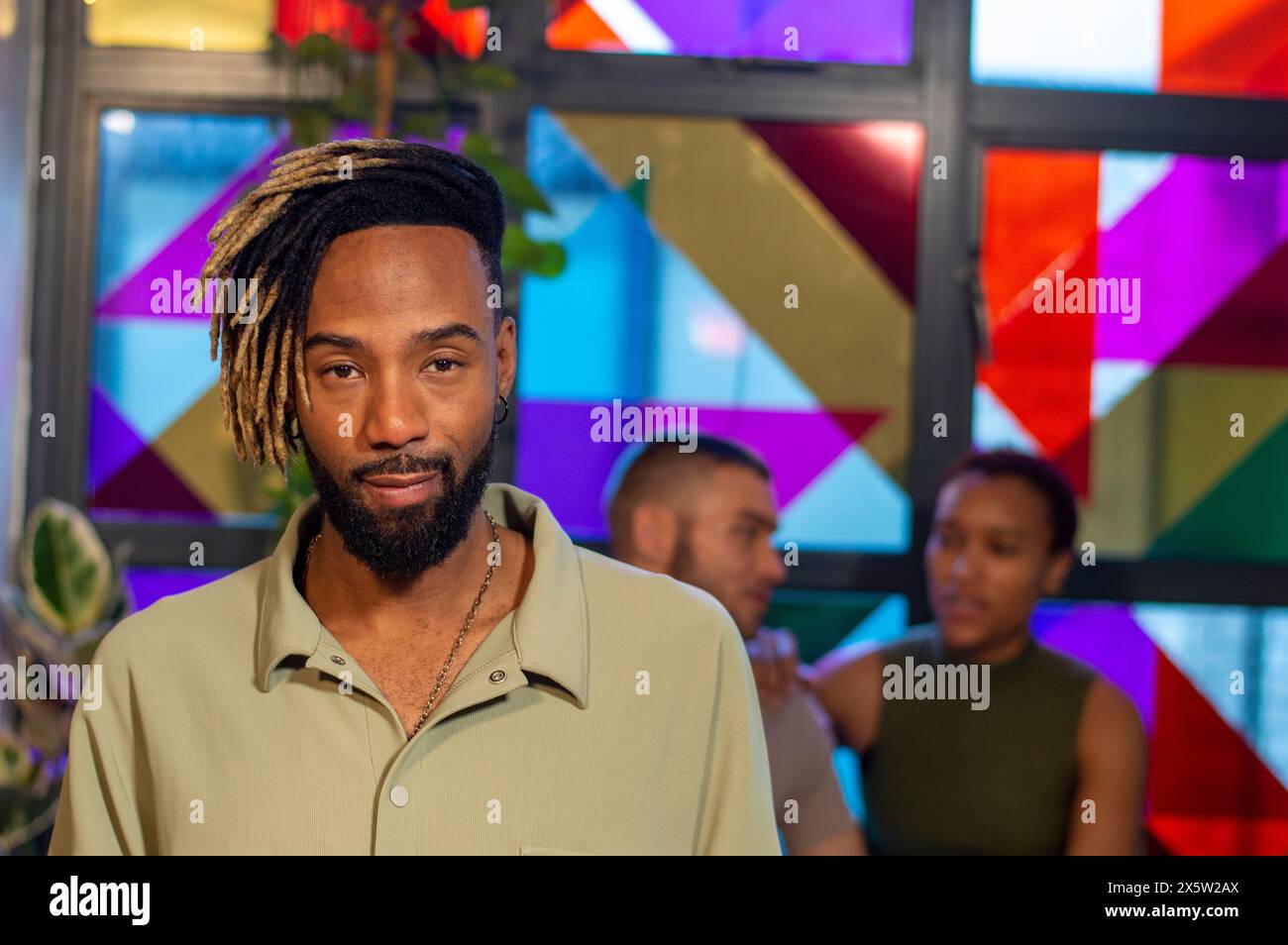 Porträt eines Mannes, der vor einem bunten Fenster steht Stockfoto