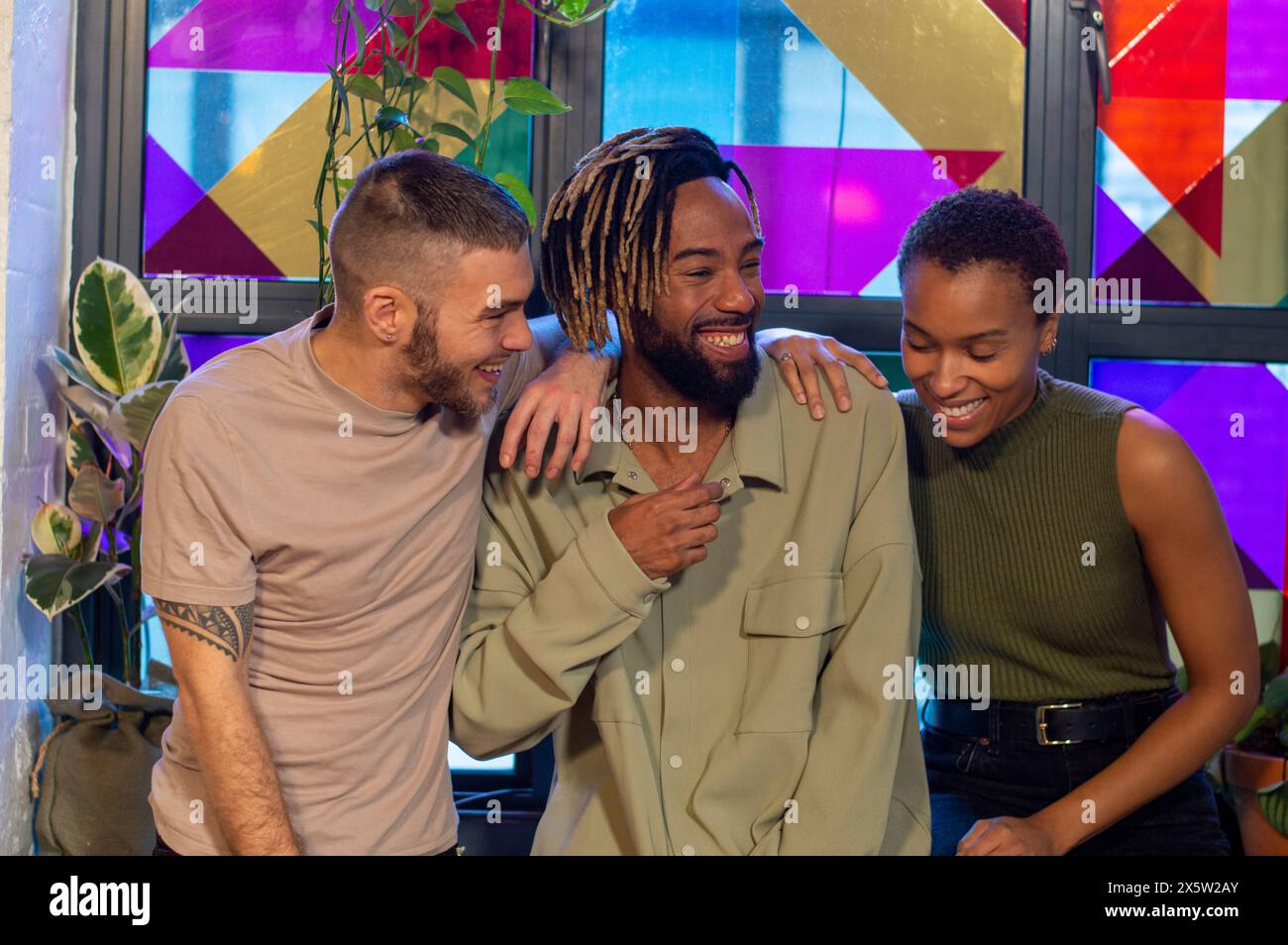 Lächelnde Freunde sitzen vor einem bunten Fenster Stockfoto