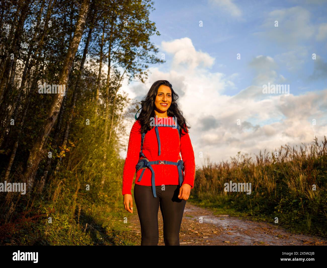 Lächelnde Frau, die durch den Wald wandert Stockfoto
