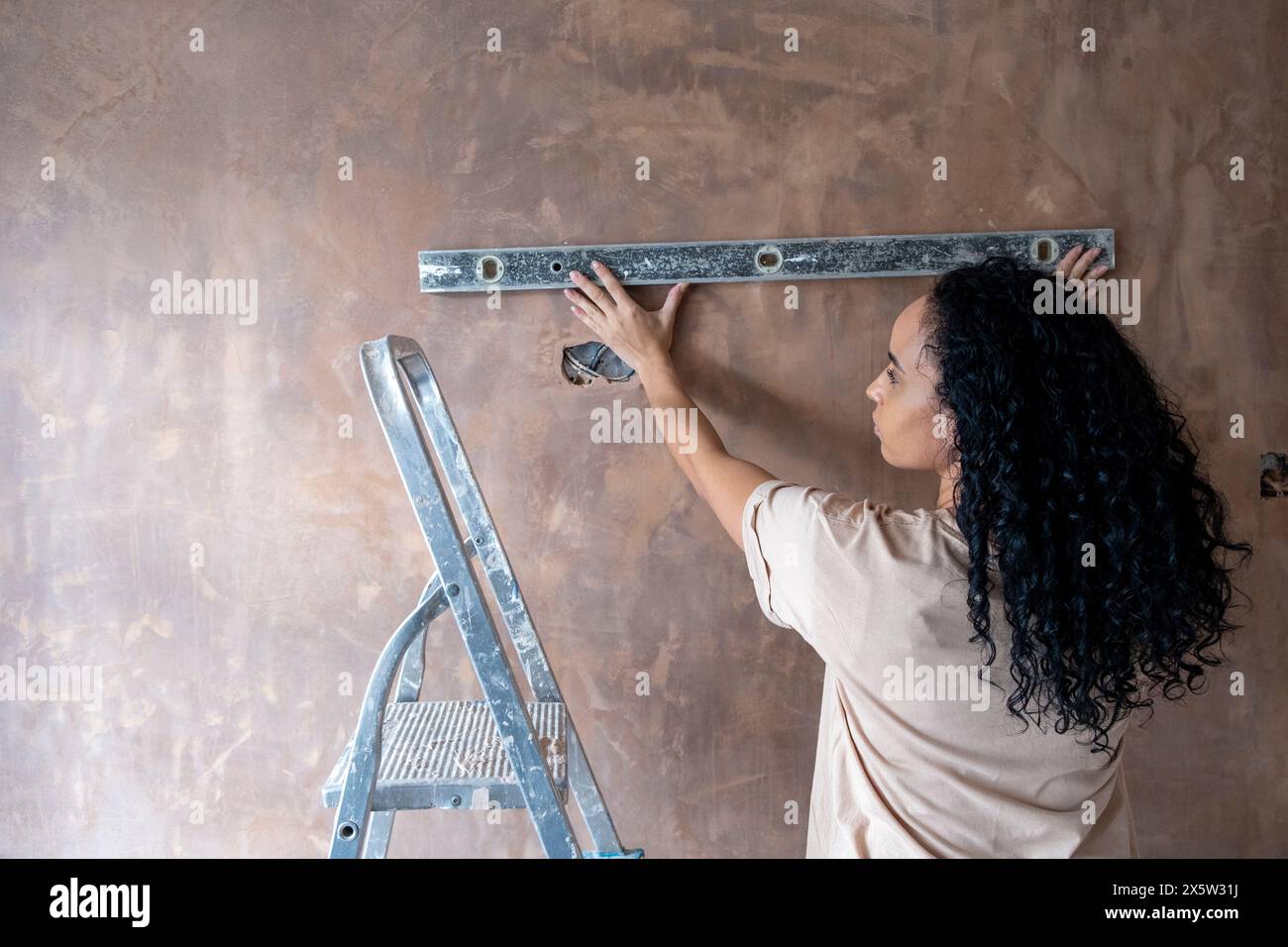 Frau, die eine Wasserwaage an der Wand benutzt Stockfoto
