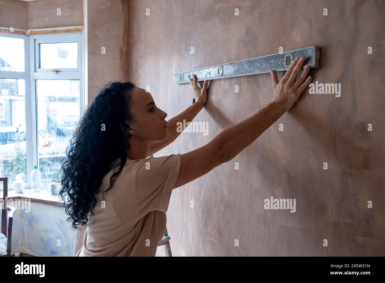 Frau, die eine Wasserwaage an der Wand benutzt Stockfoto