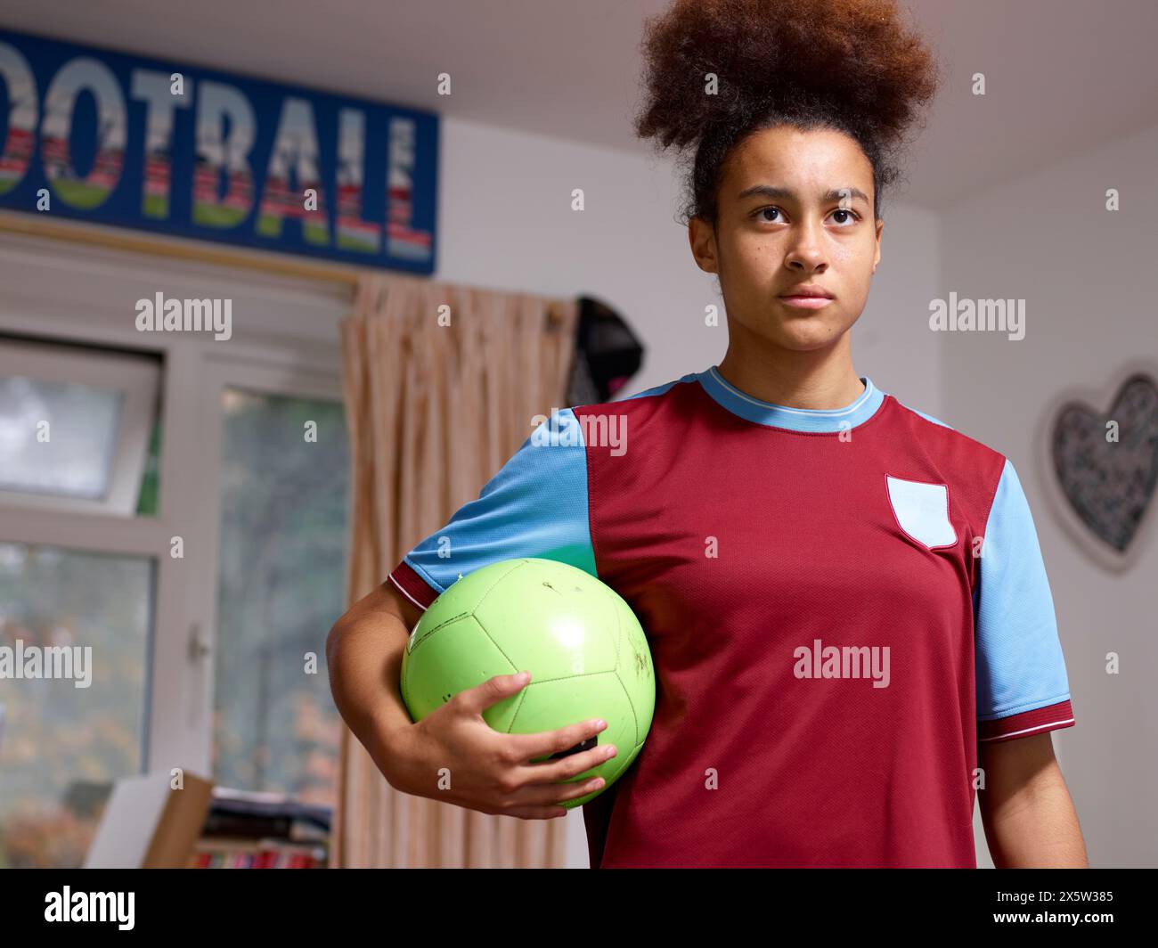 Porträt einer Fußballspielerin mit Ball zu Hause Stockfoto