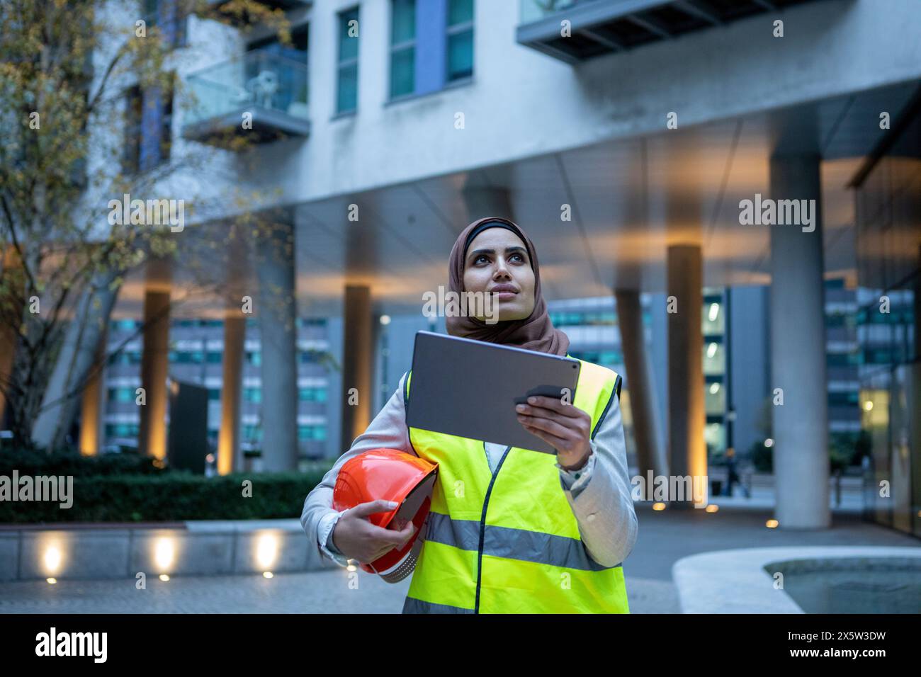 Großbritannien, London, weibliche Ingenieurin im Hijab, die ein Tablet vor dem modernen Gebäude hält Stockfoto