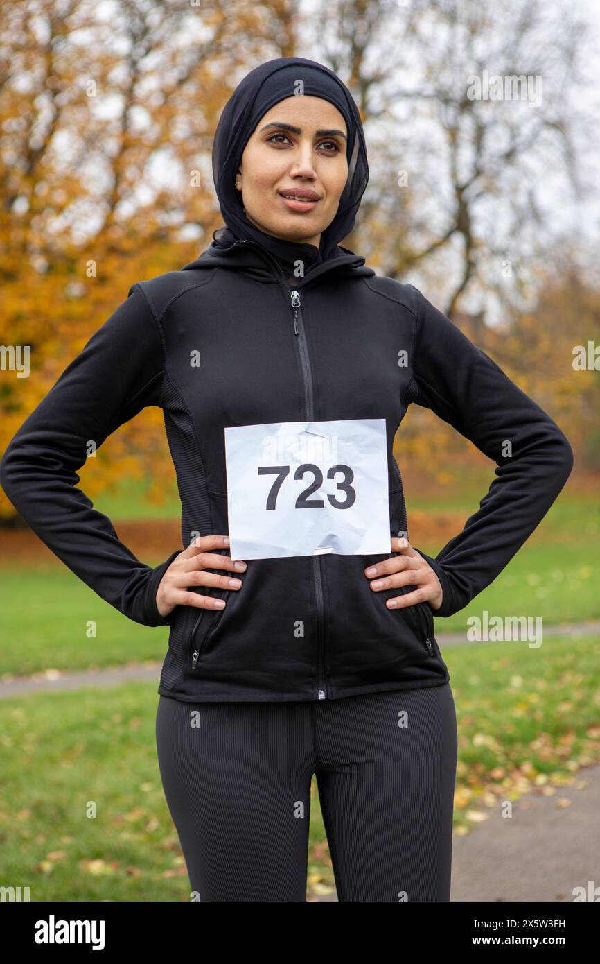 Porträt einer Frau in schwarzer Sportbekleidung und Hijab mit Rennnummer Stockfoto