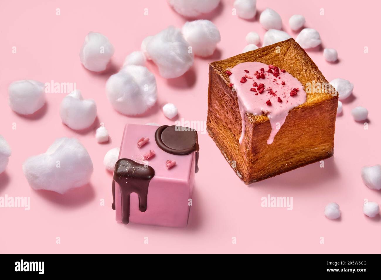 Zwei glasierte, würfelförmige Croissants mit Zuckerwatte auf Rosa Stockfoto