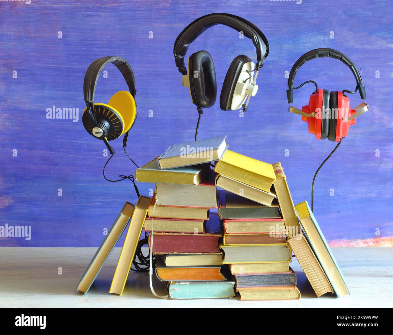 Hörbuch-Konzept mit Büchern und 3 schwimmenden Vintage-Kopfhörern, Literatur, Bildung, Unterhaltung, kostenloser Kopierraum Stockfoto