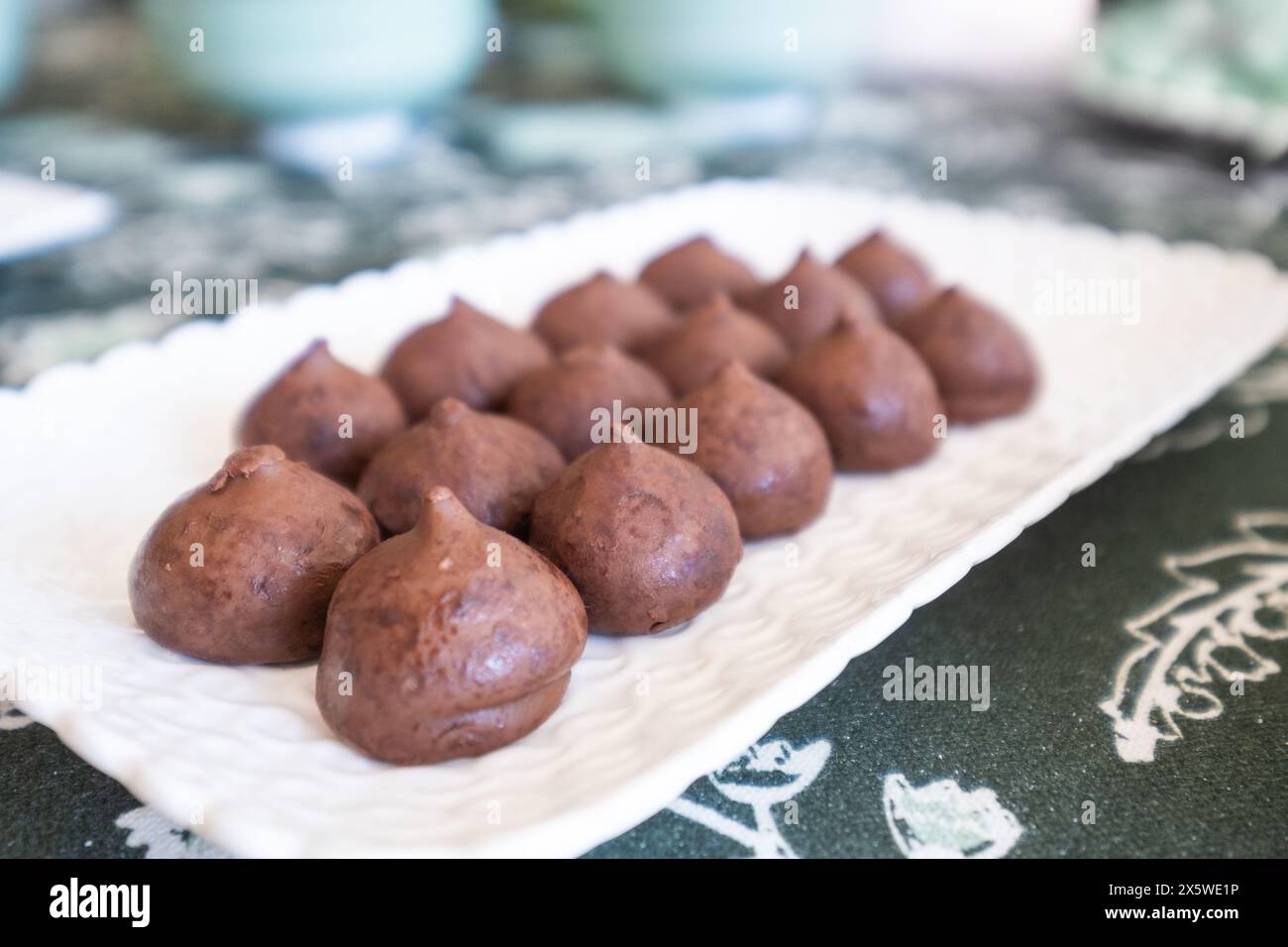 Detail eines Süßigkeitentisches. Eine weiße Porzellanschale mit exquisiten Schokoladentrüffeln oder Bonbons Stockfoto