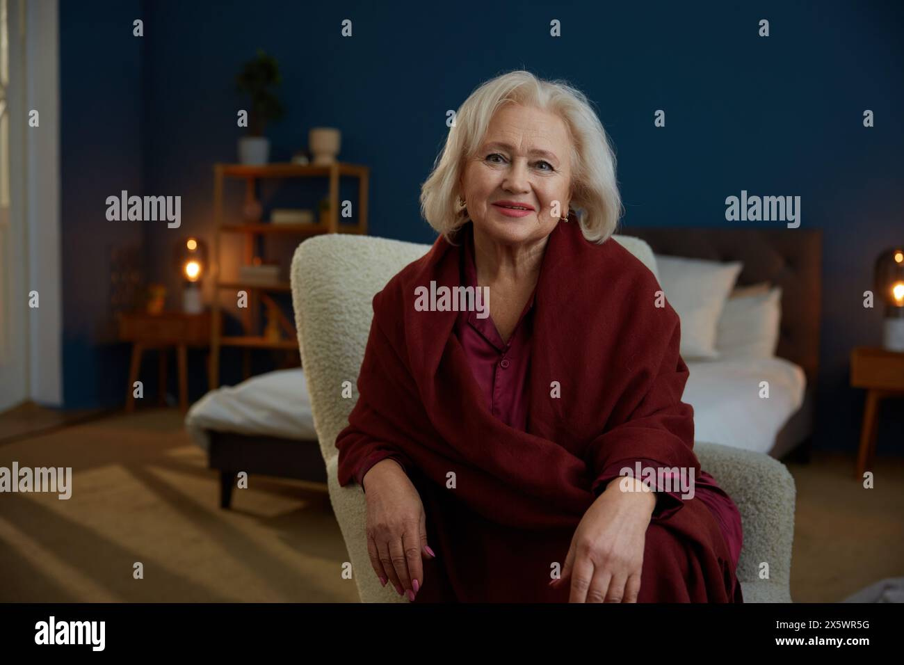 Porträt einer schönen gepflegten Seniorin, die zu Hause auf einem Sessel sitzt Stockfoto