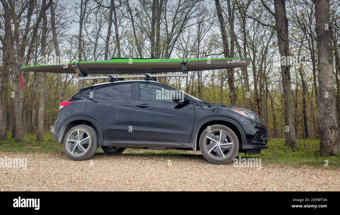 Rosebud, MO, USA – 20. April 2024: Ein herausragendes Rennkayak auf Dachträgern des Honda HR-V SUV auf einem Waldparkplatz. Stockfoto