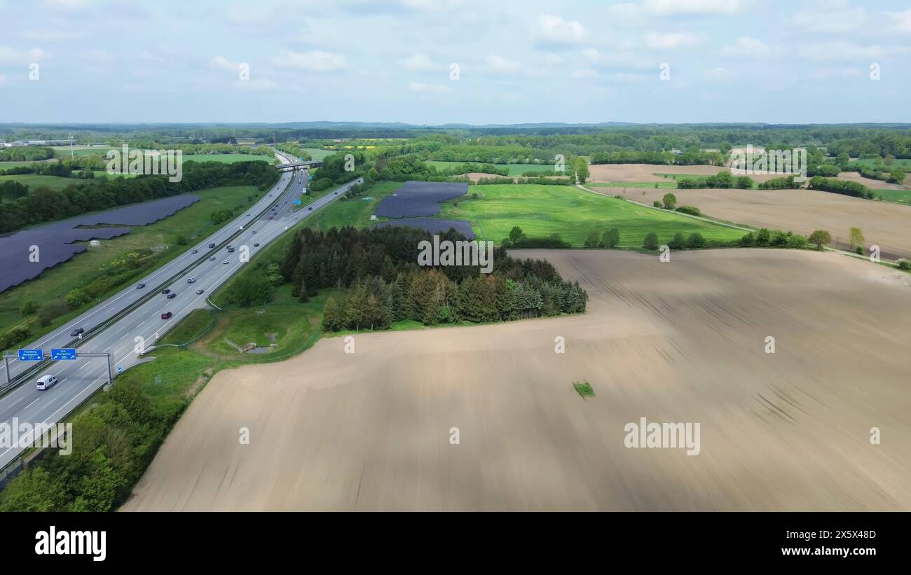 Drohnenflug auf einer deutschen Autobahn mit viel Verkehr und großen Solarpaneelen neben der Straße Stockfoto