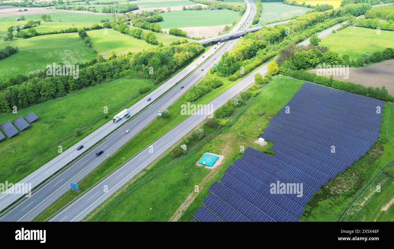 Drohnenflug auf einer deutschen Autobahn mit viel Verkehr und großen Solarpaneelen neben der Straße Stockfoto