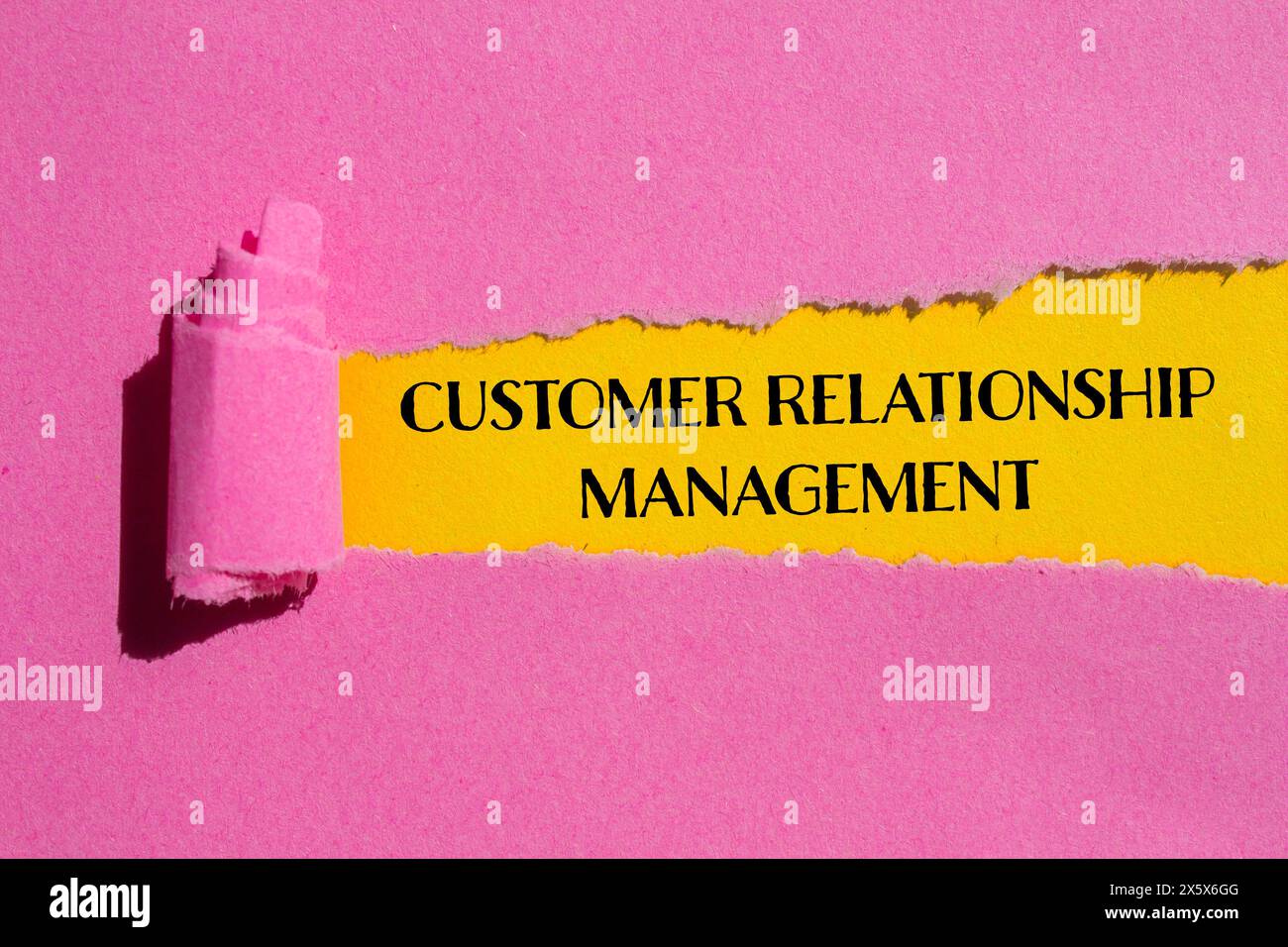 Wörter zum Kundenbeziehungsmanagement auf gerissenem rosafarbenem Papier mit gelbem Hintergrund. Konzeptionelles Symbol für das Kundenbeziehungsmanagement. Kopie s Stockfoto