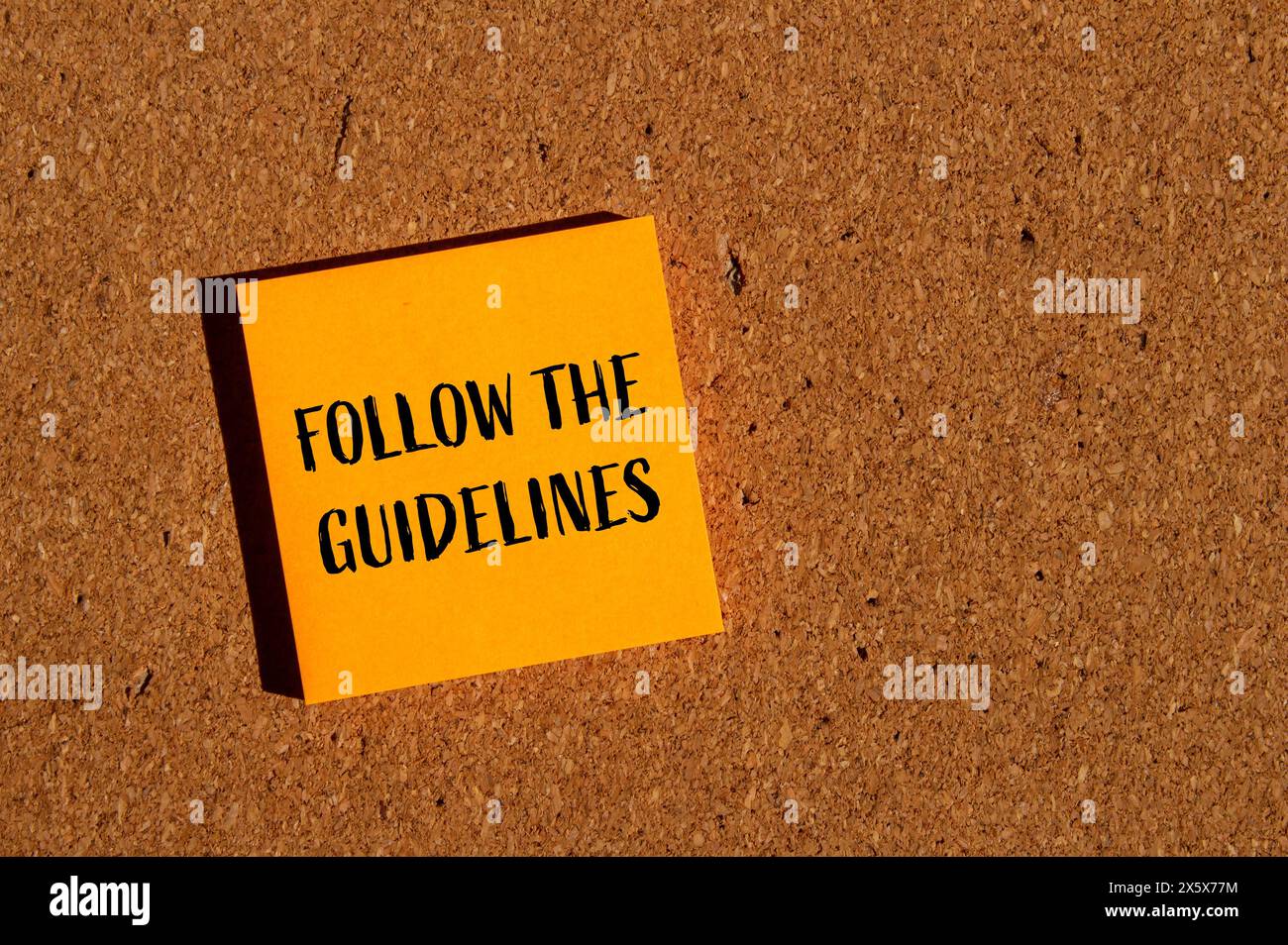 Befolgen Sie die Anweisungen auf einem orangefarbenen Papieraufkleber mit braunem Hintergrund. Konzeptionell Befolgen Sie das Richtliniensymbol. Kopierbereich. Stockfoto