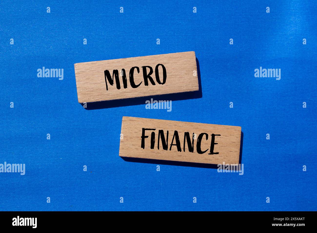 Wörter aus dem Mikrofinanzbereich auf Holzblöcken mit blauem Hintergrund. Konzeptionelles Geschäftssymbol für Mikrofinanzen. Kopierbereich. Stockfoto