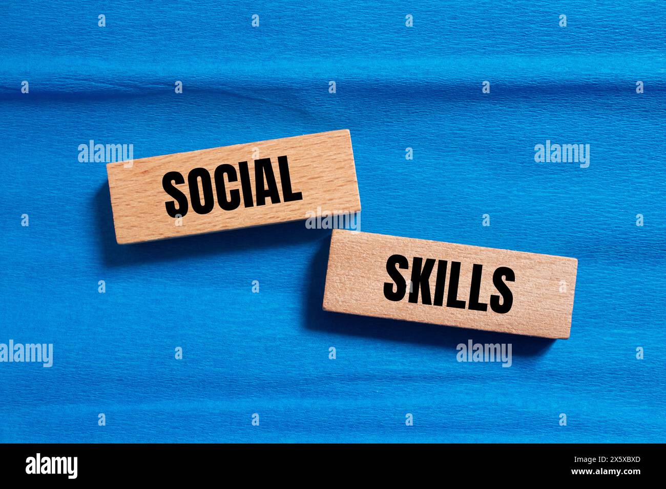 Wörter für soziale Fähigkeiten, geschrieben auf Holzblöcken mit blauem Hintergrund. Symbol für konzeptionelle soziale Fähigkeiten. Kopierbereich. Stockfoto