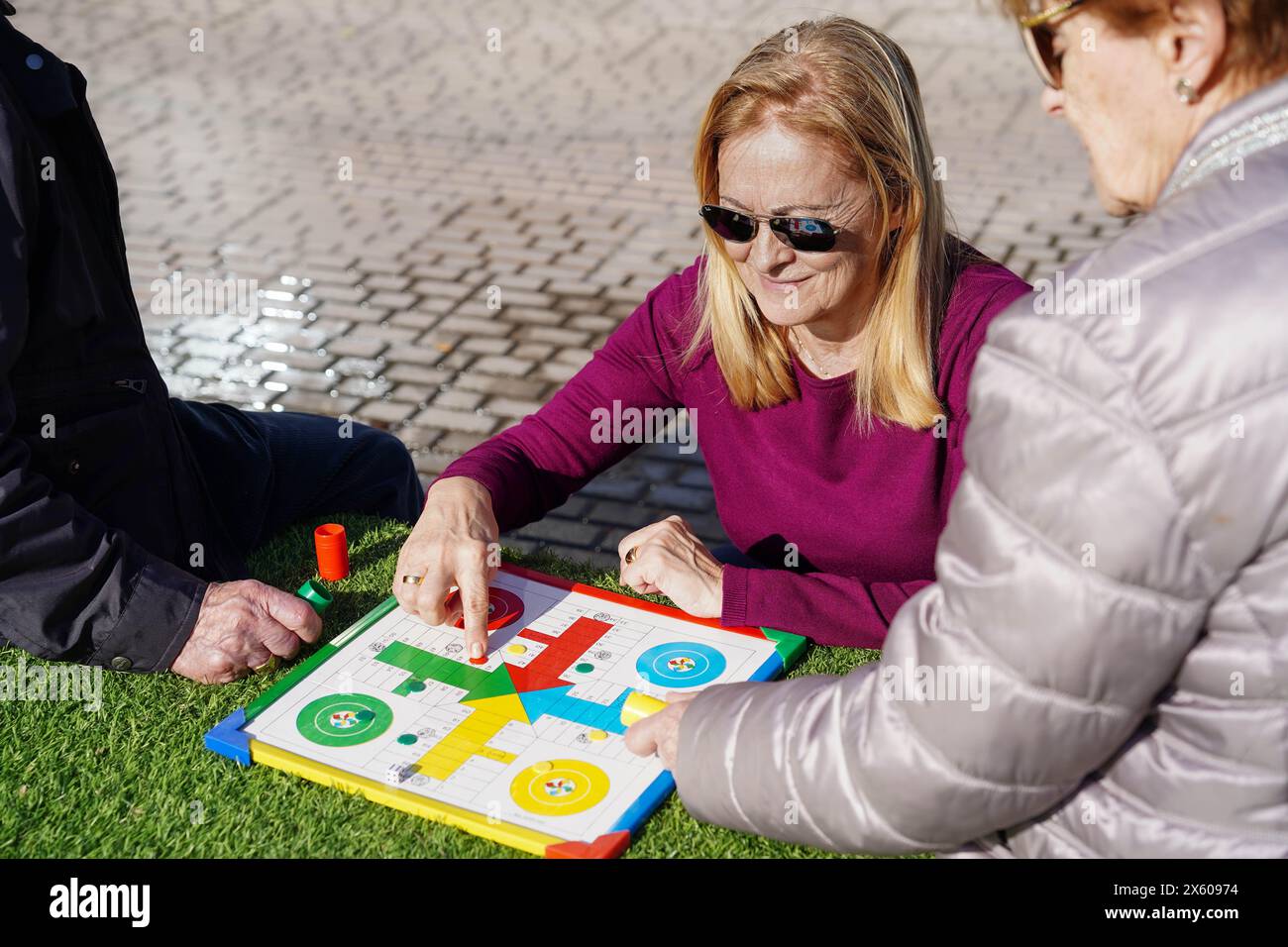 Ein Betreuer spielt ein Erinnerungsspiel mit zwei älteren Menschen. Stockfoto